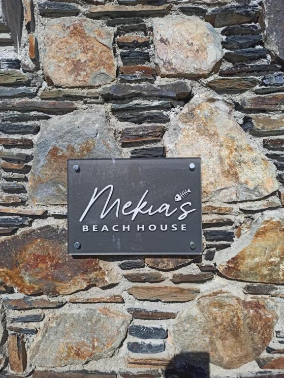 a sign for a beach house on a stone wall at Mekia's beach house in Livadia