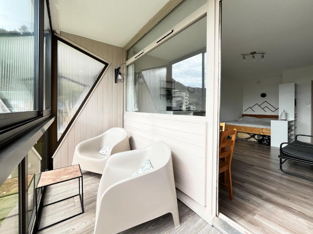 une chambre avec deux chaises blanches et une fenêtre dans l'établissement Appartement - Station de ski, à La Bresse