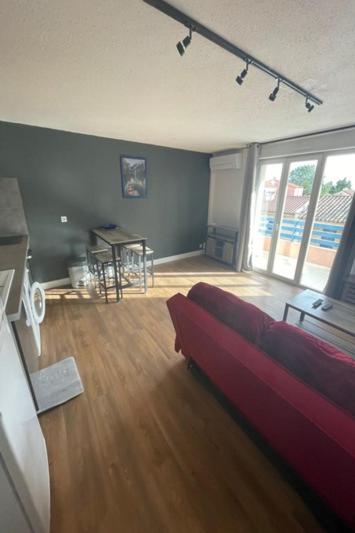 - un salon avec un canapé rouge et du parquet dans l'établissement Magnifique T2 - Émeraude 41, à Canet