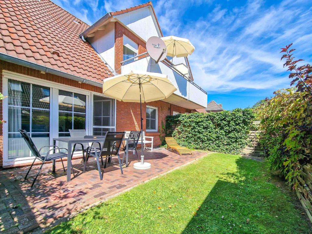 a patio with a table and chairs and an umbrella at Silbermöwe in Greetsiel
