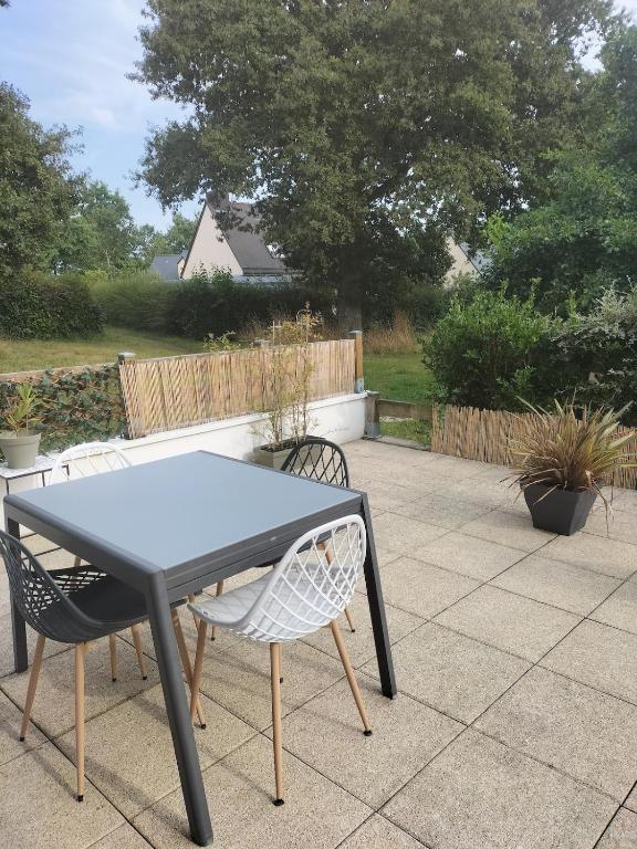 une table noire et des chaises sur une terrasse dans l'établissement Appartement avec terrasse, à Guichen