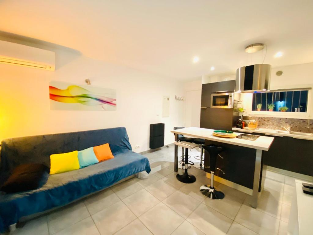 un salon avec un canapé bleu et une cuisine dans l'établissement Appartement T2, 5mn à pied de la plage et du port de Sanary, à Six-Fours-les-Plages