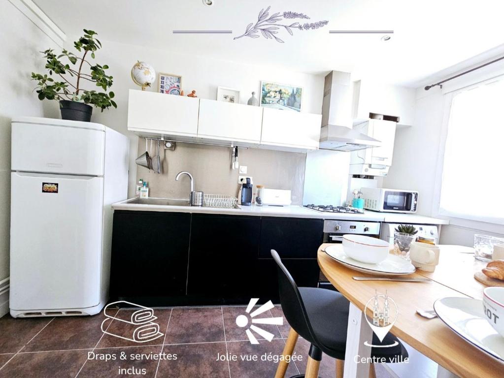 une cuisine avec un réfrigérateur blanc et une table dans l'établissement L'Ensoleillé - Central, Wifi & Confort, à Rodez