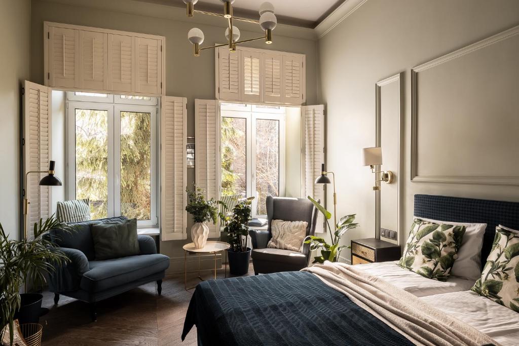 a bedroom with a bed and two chairs and windows at Moja apartments in Kraków