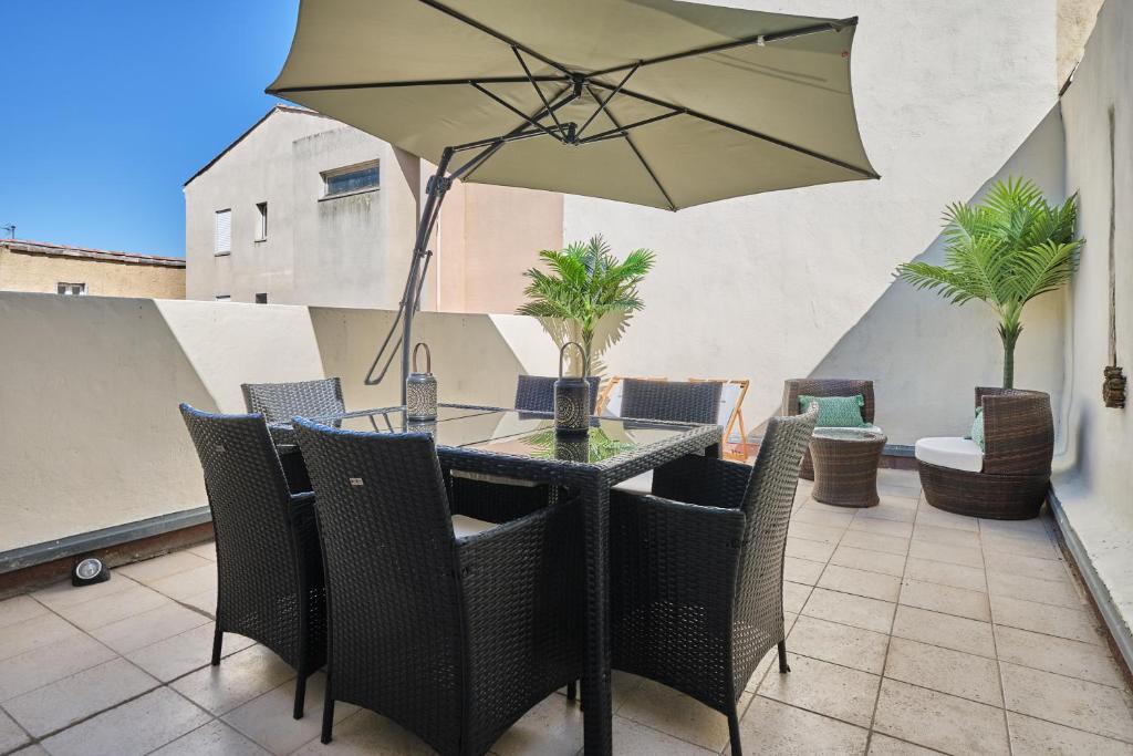 une table avec des chaises et un parasol sur une terrasse dans l'établissement Spacieux Appartement Climatisé au centre-ville de Narbonne, à Narbonne