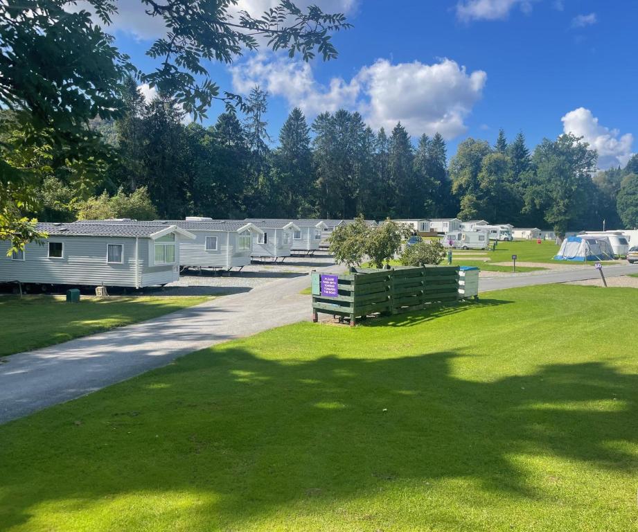 a park with a bench in the grass next to a road at Faskally Woods Holiday Park in Pitlochry