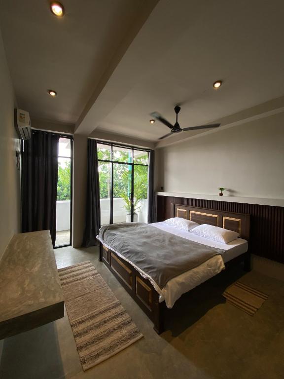 a bedroom with a large bed and a large window at Surf's Up LOFT in Weligama