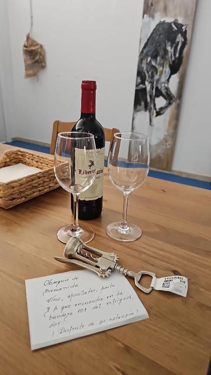 a bottle of wine and two glasses on a table at Blue Mango Surf House Center in Puerto del Rosario