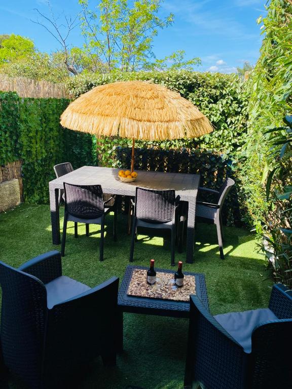 une table et des chaises avec un parasol en paille dans l'établissement Villa Club Mer Belle, à Sanary-sur-Mer