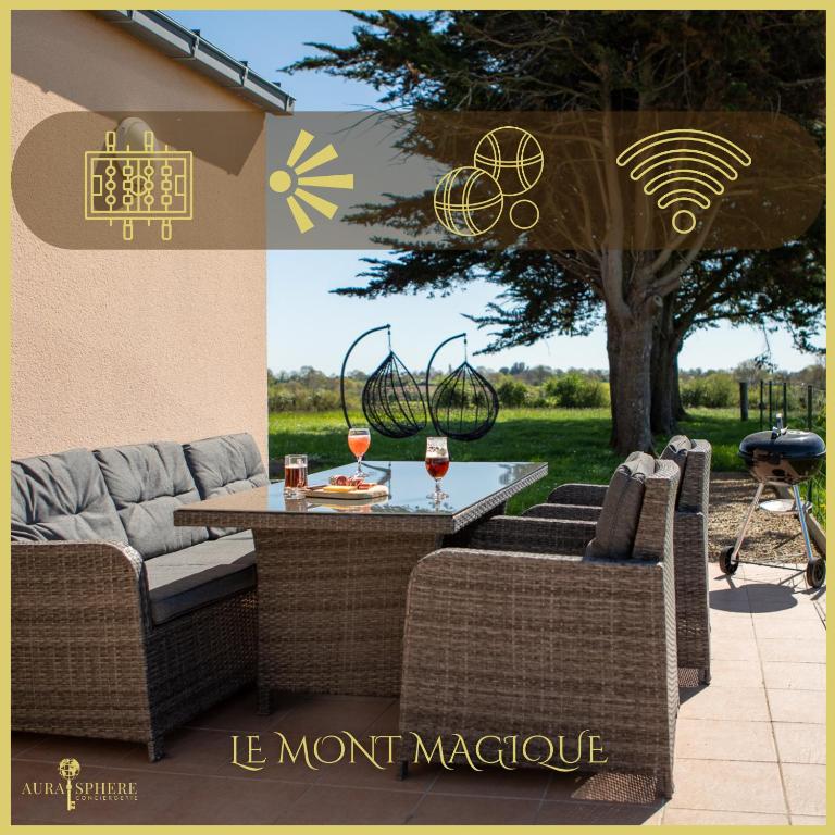 une terrasse avec un canapé et une table avec des verres de vin dans l'établissement Vue Mt-St-Michel, Élégance, calme et baby-foot Bonzini, à Dragey-Ronthon