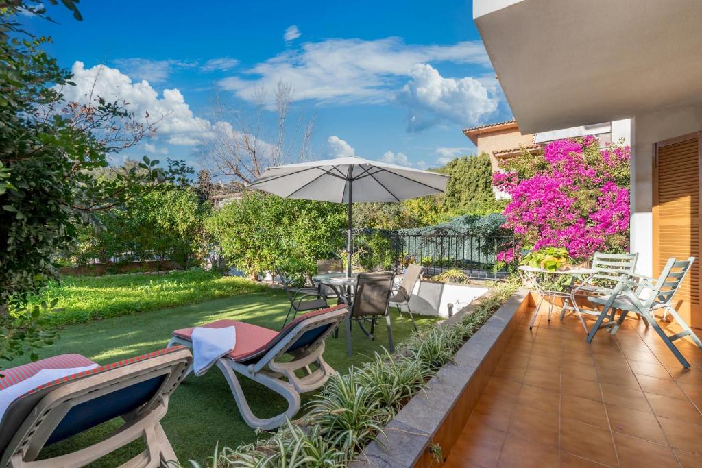 a patio with chairs and an umbrella in a yard at Apartament Al Mare in Port de Soller