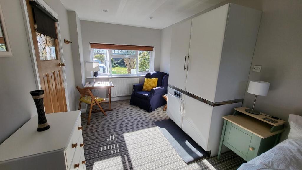 a room with a bed and a blue chair at Home for one! in Midford