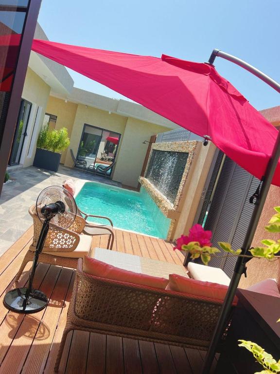 een roze parasol op een terras naast een zwembad bij Les Résidences KYM in Yamoussoukro