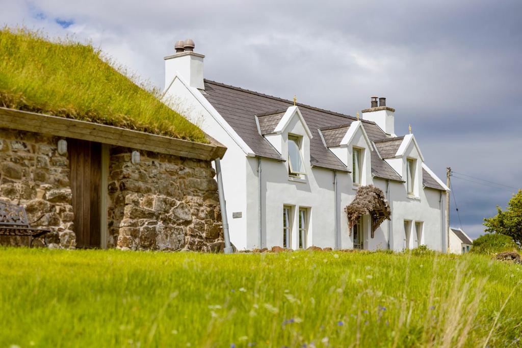 una grande casa bianca con tetto in erba di Mint Croft Luxury Self-Catering Cottages a Geary