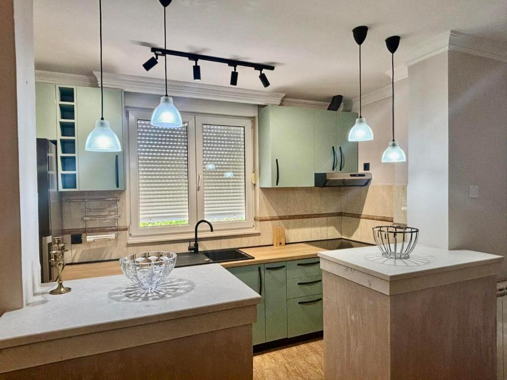 a kitchen with green cabinets and pendant lights at Gold Lux in Podgorica