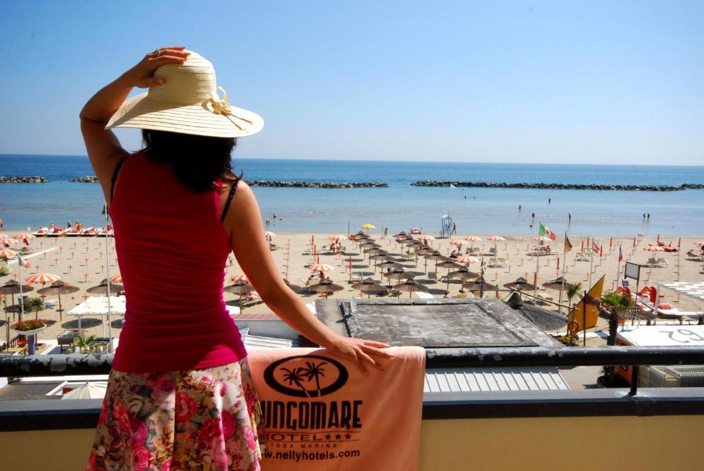 Eine Frau steht auf einem Balkon mit Blick auf den Strand in der Unterkunft Hotel Lungomare in Bellaria-Igea Marina