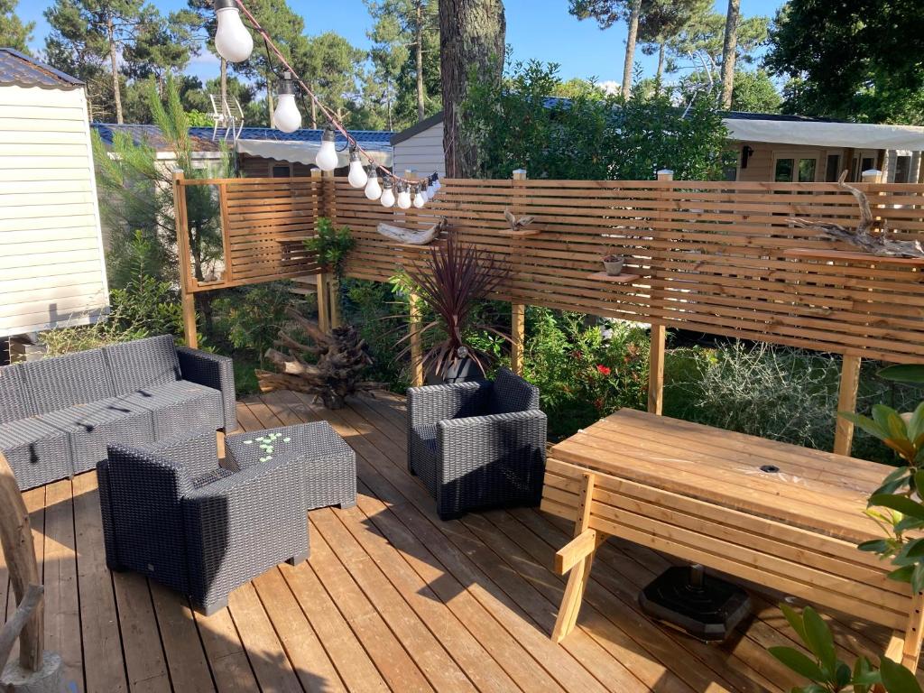 a wooden deck with a bench and a table at Charmant mobil home camping Les Embruns in Lège-Cap-Ferret