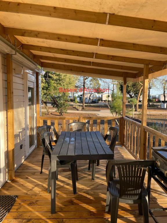 une terrasse en bois avec une table de pique-nique et des chaises dans l'établissement Mobil Home Lège Cap ferret bassin, à Lège-Cap-Ferret