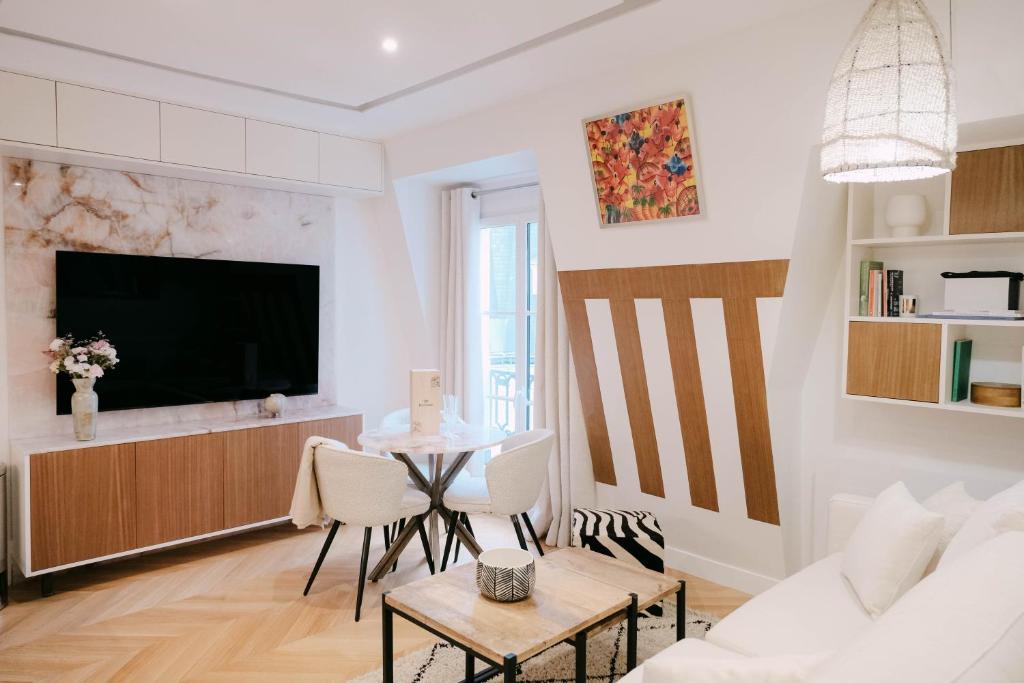 un salon avec une télévision et une table dans l'établissement SaintGermainByCecile - Luxueux 2 pièces AC Bianca, à Paris