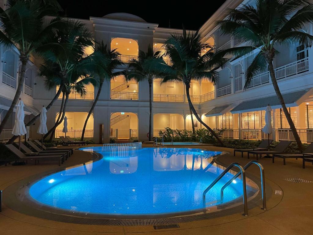 a large swimming pool in front of a building with palm trees at Outrigger Koh Samui Beach Resort - SHA Extra Plus in Lamai