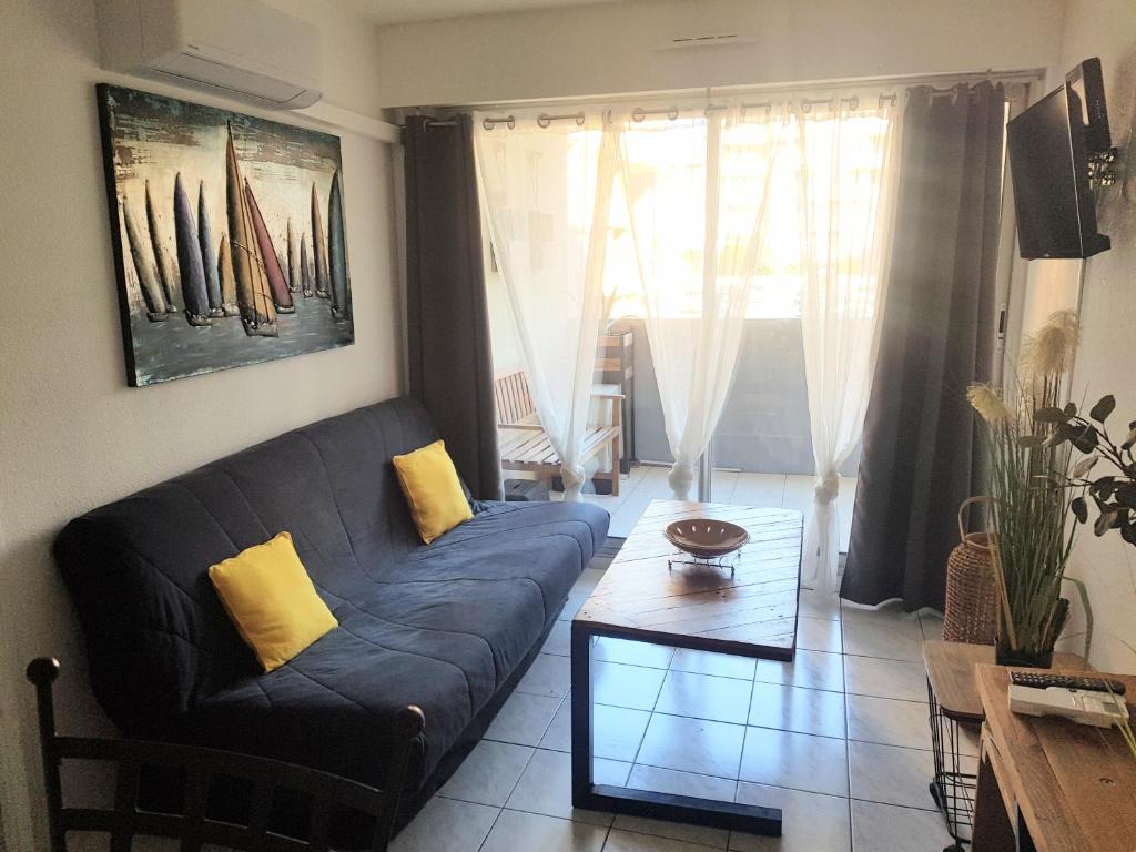 un salon avec un canapé et une table dans l'établissement Le Vénizio - Classé 2 étoiles - T2 climatisé, avec terrasse, parking, prêt de vélos, 10 minutes à pied gare et centre ville, à Sète
