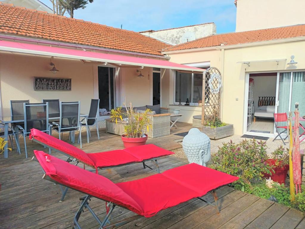 un patio avec des tables et des chaises rouges sur une terrasse dans l'établissement Maison Port de la Côtinière à 150m de la plage, à Saint-Pierre-dʼOléron