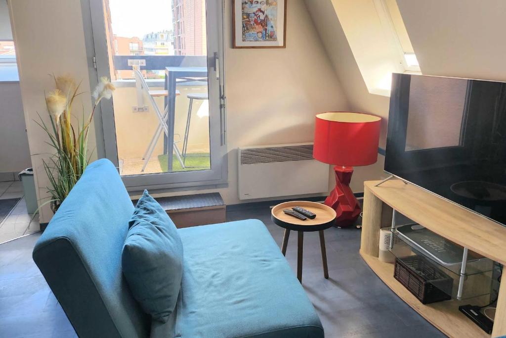 un salon avec un canapé bleu et une télévision dans l'établissement Studio for two with balcony of 20 m2 - Cabourg, à Cabourg