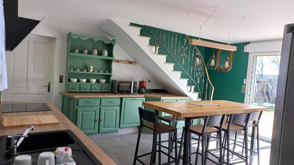 une cuisine avec des armoires vertes et un escalier dans l'établissement Gîte Chez Léon, à La Chaze-de-Peyre