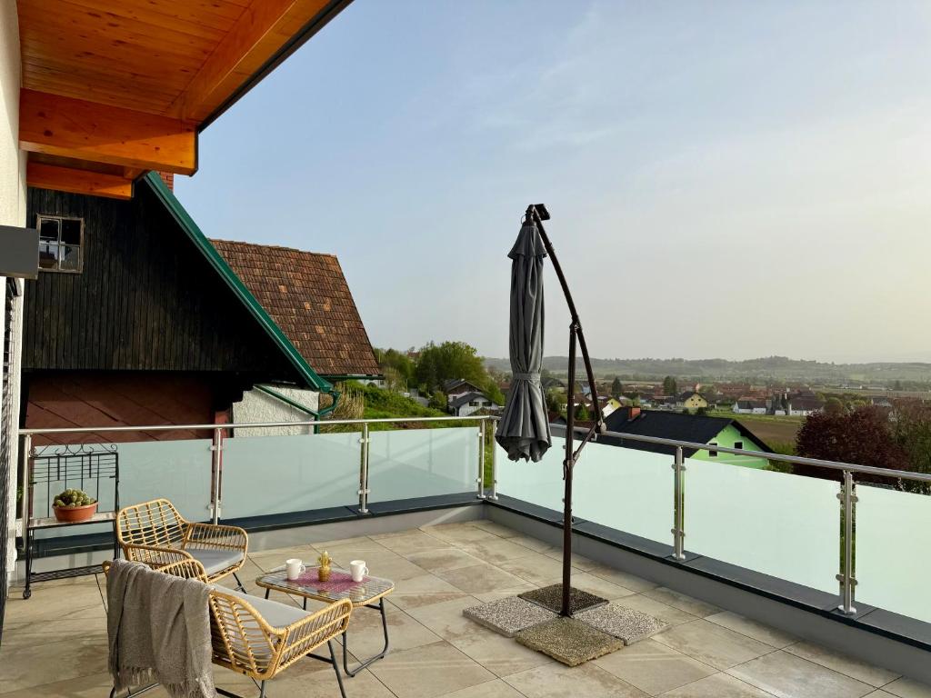 een balkon met een parasol en een tafel en stoelen bij Mc Home Neues und sonniges Doppelhaus, Top 1 mit grosse Terrasse und E-Ladestation in Dobl bei Graz in Dobl
