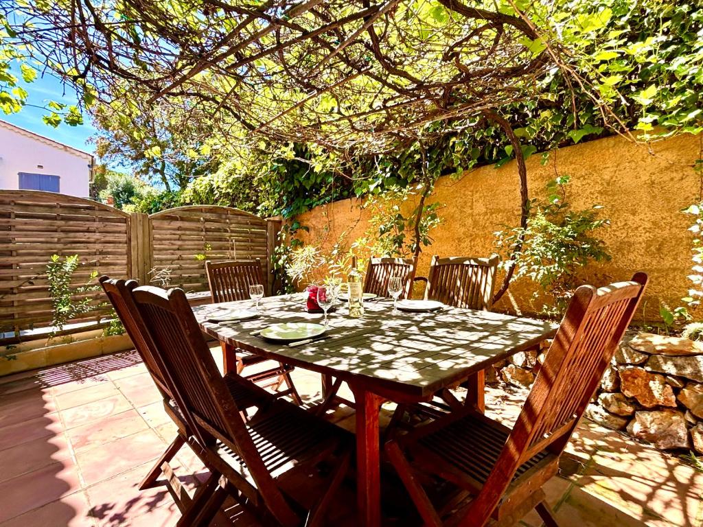 - une table en bois avec des chaises sur la terrasse dans l'établissement Le Cocon du sud proche plage Renecros, à Bandol