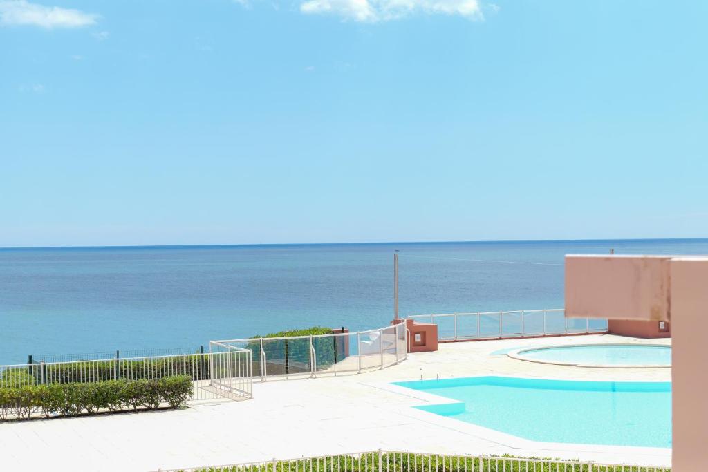 une piscine avec l'océan en arrière-plan dans l'établissement Appartement Piscine Front de mer 43 m2, Sète, à Sète
