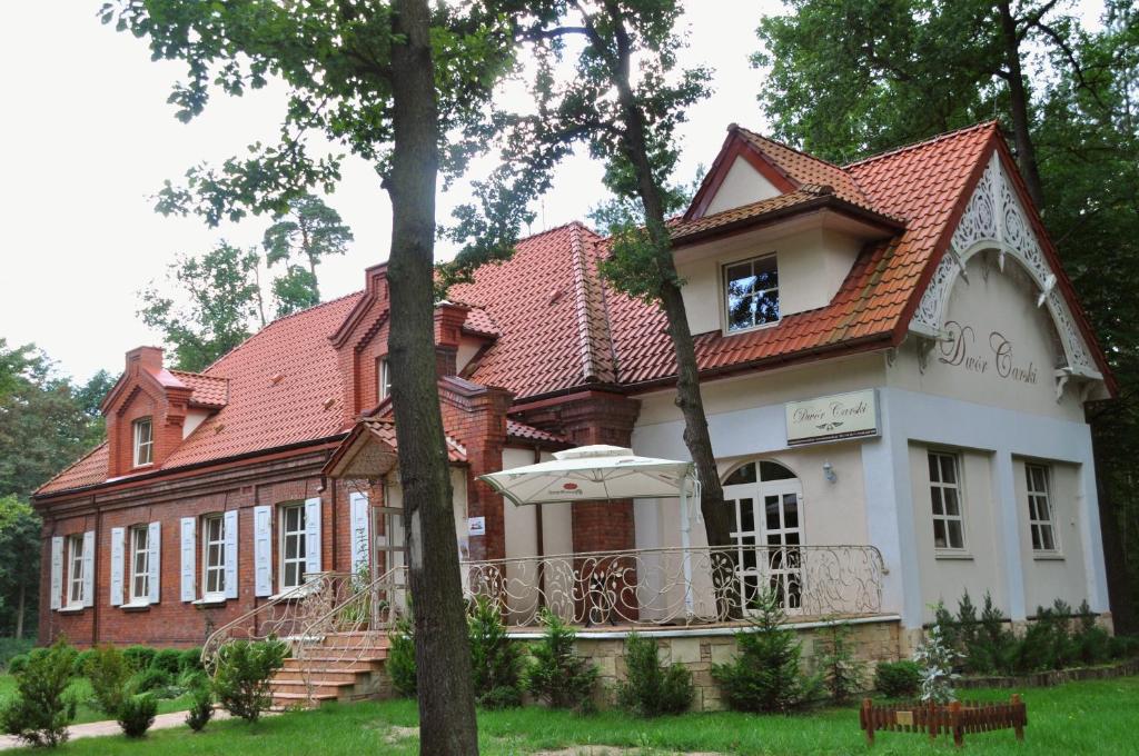 une grande maison avec un toit rouge dans l'établissement Dwór Carski, à Spała