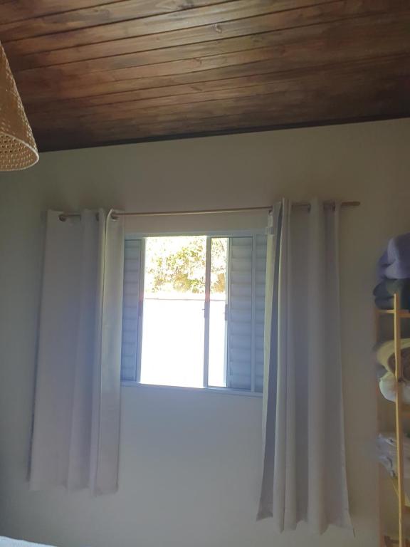 a window with white curtains in a room at Chalé Canto da Montanha in São José dos Campos