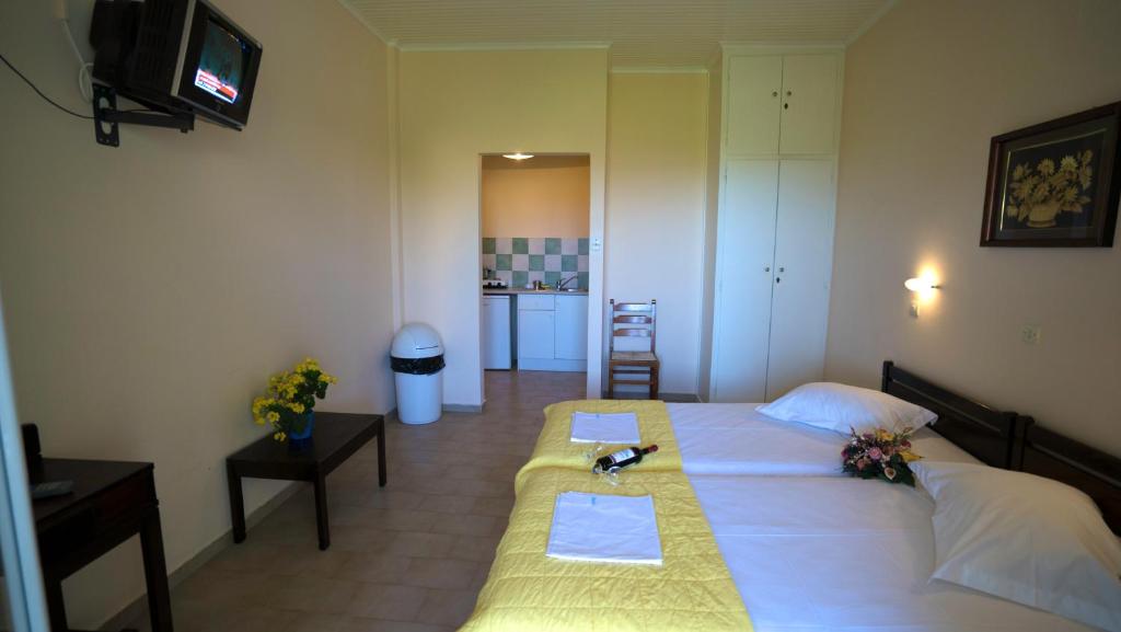 una camera da letto con un grande letto con due tavoli e una televisione di Meltemi Standard Studios a Kalamákion