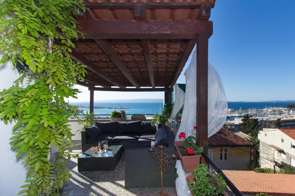 une terrasse avec un canapé sous une pergola en bois dans l'établissement Apartments Vinko, à Split