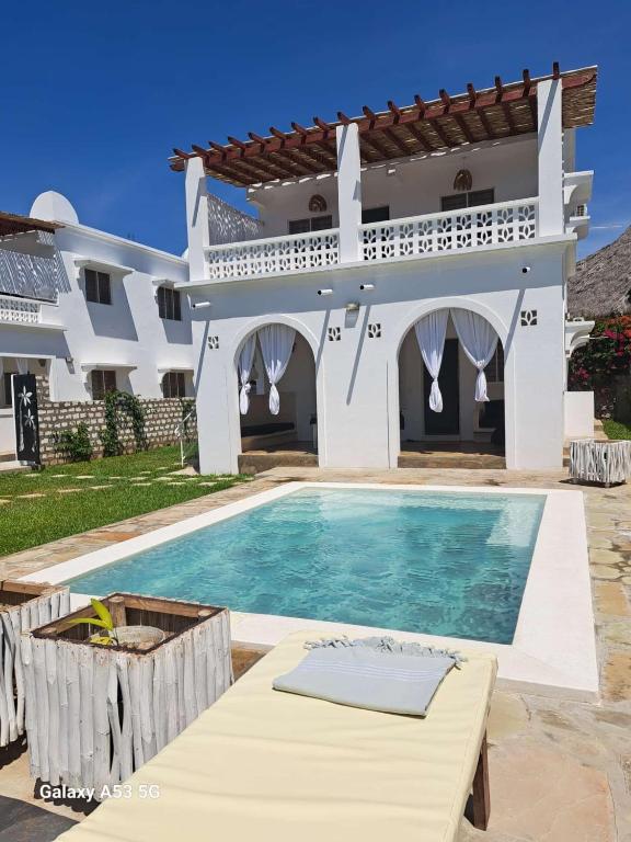 a villa with a swimming pool in front of a house at airaMIudi in Watamu