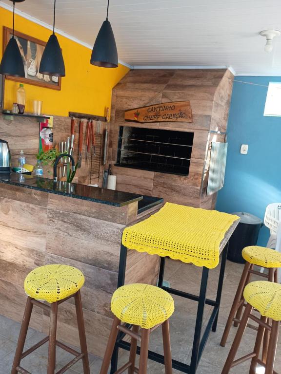 a kitchen with a yellow table and stools at Casa familiar rua 13 maio número 1639 in Rosário do Sul