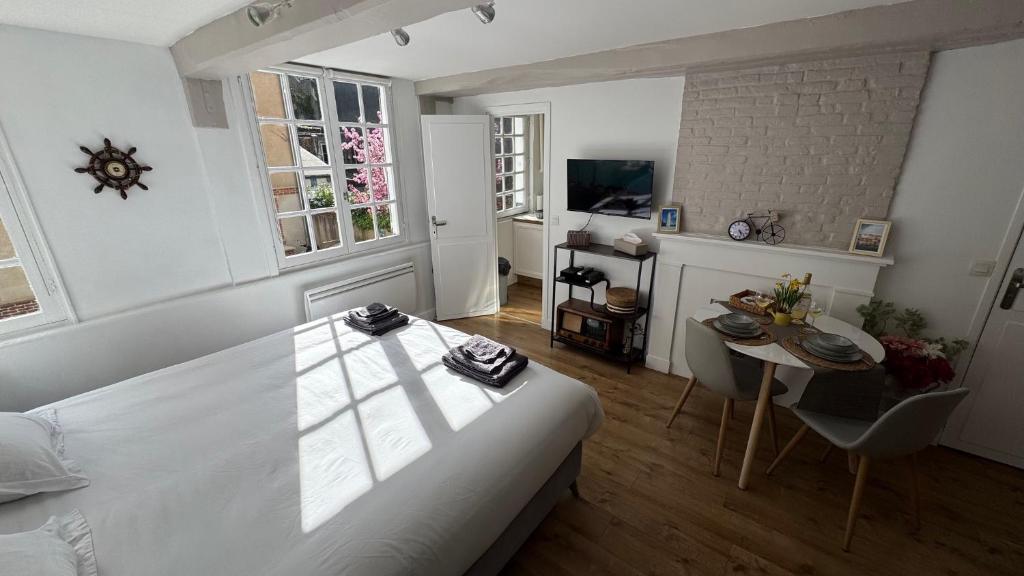 een slaapkamer met een wit bed, een tafel en een bureau bij Appartement rénové 250m du port - classé 3 étoiles in Honfleur