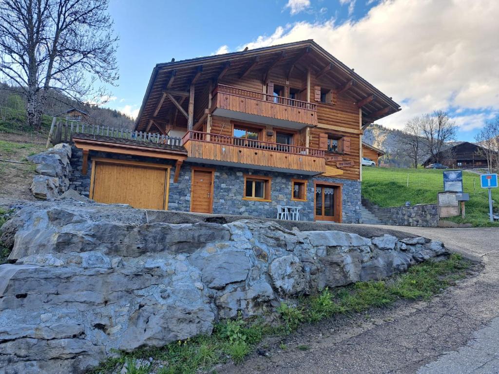 dom z bali z balkonem na szczycie skały w obiekcie Appartement cosy face aux Aravis w mieście Le Grand-Bornand