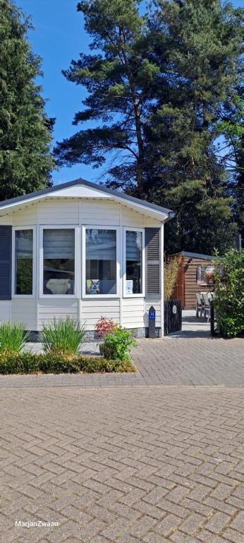 a small white house with windows on a patio at De Bosuil in Putten