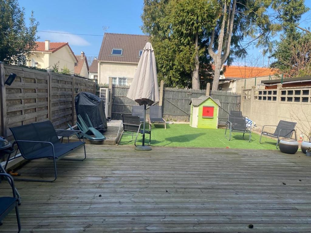une terrasse avec un parasol, des chaises et une cour dans l'établissement Les Pommiers, à Argenteuil