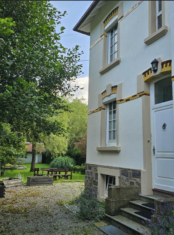 une maison blanche avec une porte blanche et un banc dans l'établissement Maison Le Beauregard Bussang, à Bussang