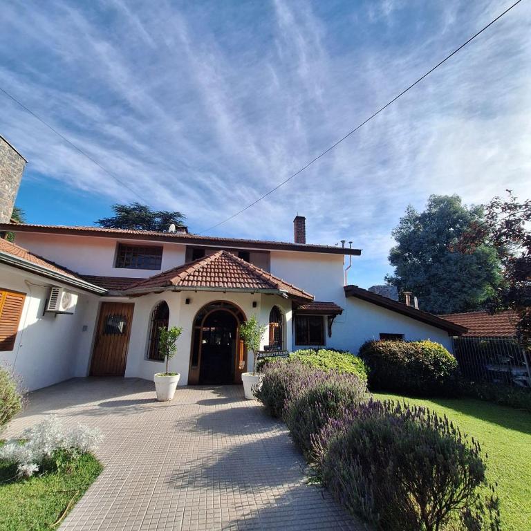 a large white house with a driveway at Hostal La Merced in Villa General Belgrano