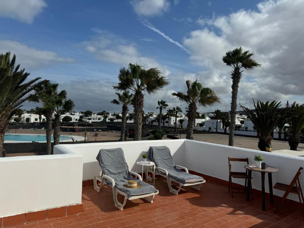 Un patio con sillas y una piscina y palmeras. en casa Valentina, en Playa Blanca