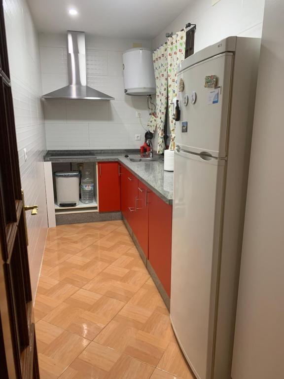 a kitchen with red cabinets and a white refrigerator at Casa Abuela Cati in Sanlúcar de Guadiana