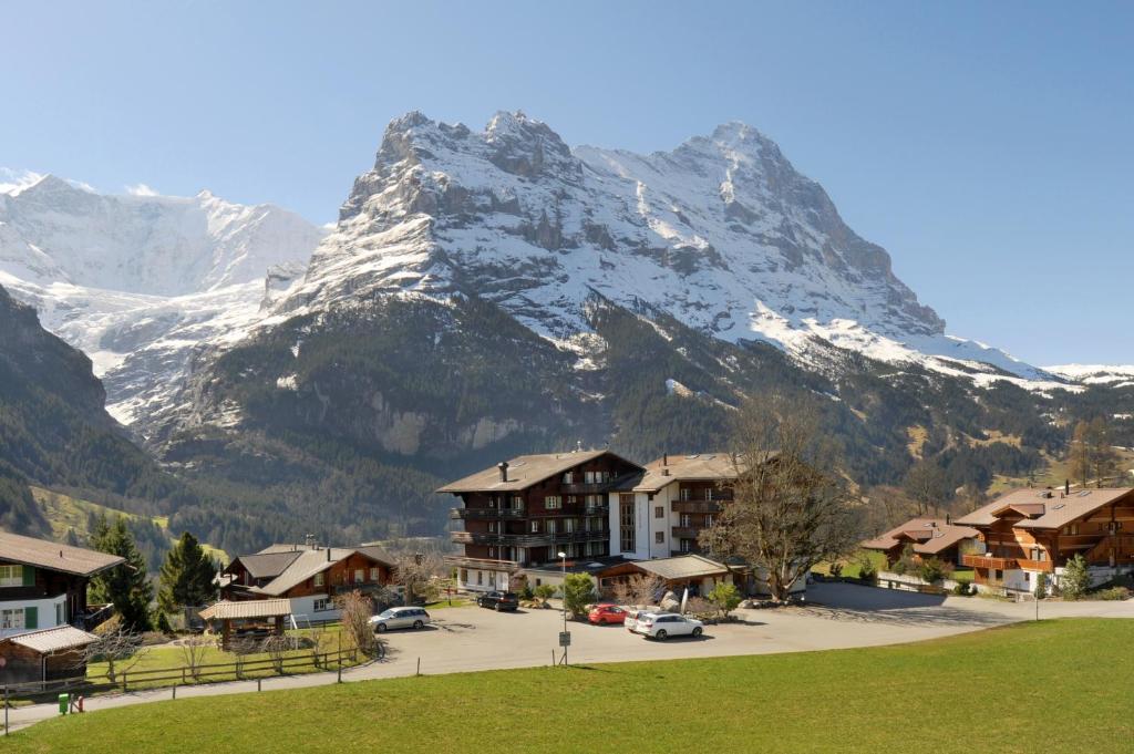 a snow covered mountain in front of a town with houses at Hotel Kirchbühl Superior in Grindelwald