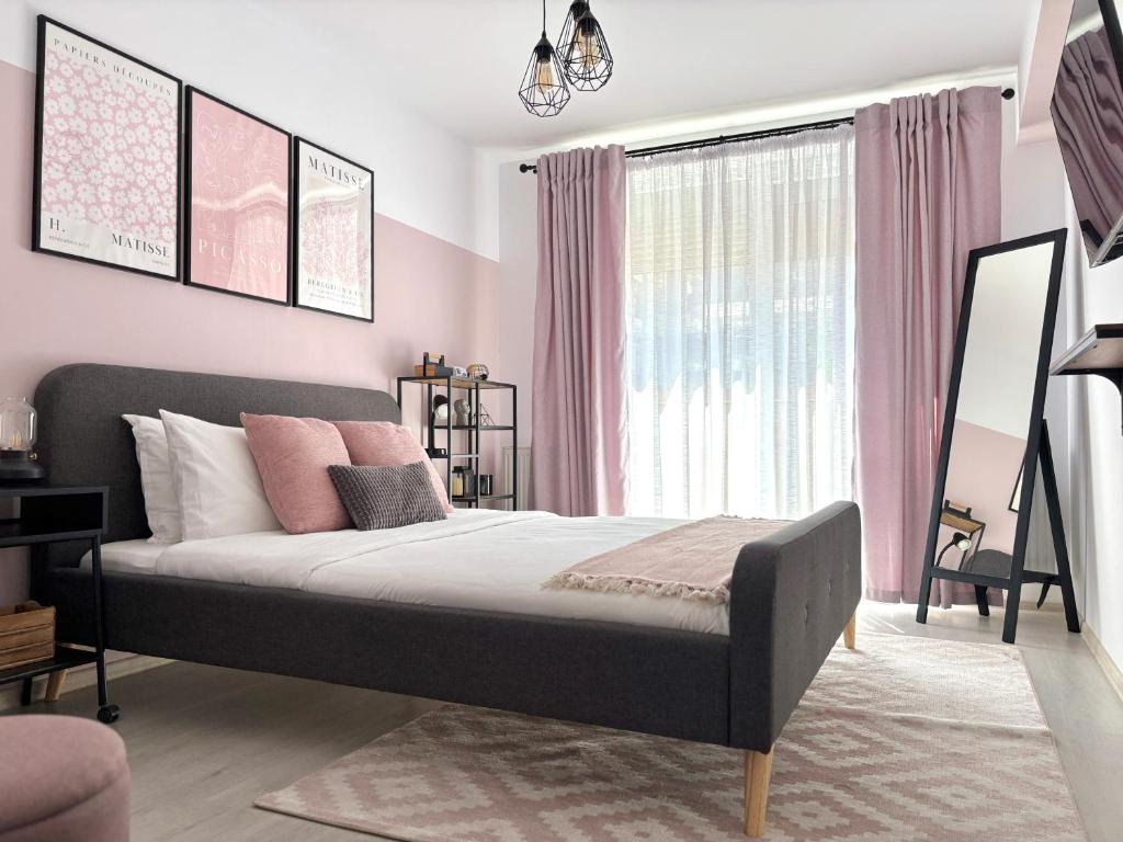ein Schlafzimmer mit einem großen Bett mit rosa Wänden in der Unterkunft Wanderlust Home Pink, Rasnov Apt for 4, Wifi and Free Parking in Râșnov
