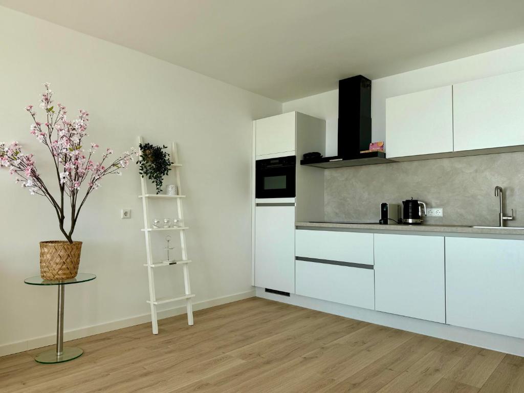een keuken met witte kasten en een tafel met een plant bij Sunset Beach in Zandvoort