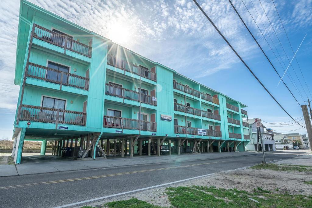 a blue building with balconies on a street at Winds VI F3 by Carolina Beach Realty in Carolina Beach