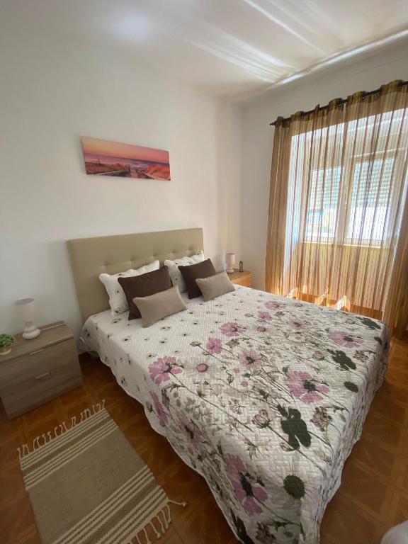 a bedroom with a bed with a floral bedspread at Casa São Marcos in Peniche